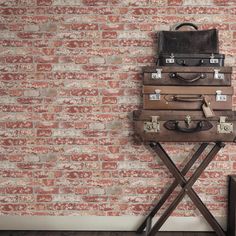 a stack of suitcases sitting on top of a table next to a brick wall