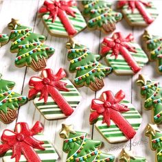 decorated christmas cookies on a white table with red bows and green striped boxes in the shape of presents