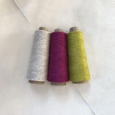 three spools of yarn sitting next to each other on top of a white surface