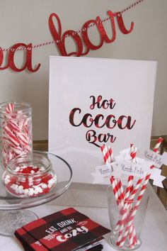 a table topped with lots of red and white candy canes next to a sign that says hot cocoa bar