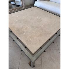 a square coffee table sitting on top of a tile floor next to a white couch