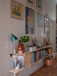 there is a shelf with books and plants on it in the room next to pictures