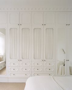 a bedroom with white furniture and carpeted flooring