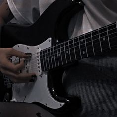 a man is playing an electric guitar in the dark with his hand on it's neck