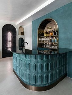 a bar with blue walls and an arched glass door in the center is filled with liquor bottles