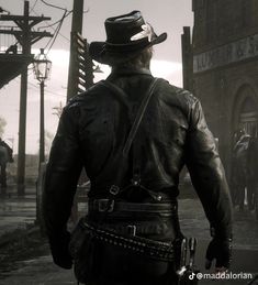 a man in a hat and leather jacket walking down a street