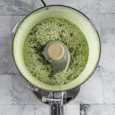 a blender filled with green stuff on top of a marble countertop next to a tile floor