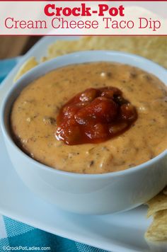 a bowl of cream cheese taco dip with tortilla chips on the side