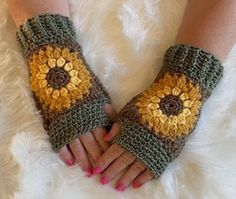 a woman's hands wearing crocheted gloves with sunflowers on them