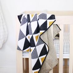 a black and white blanket sitting on top of a crib