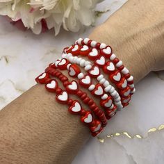 the red and white bracelets are decorated with heart shaped beads on each one arm