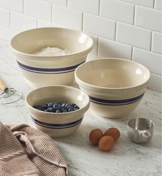 three bowls with blueberries and eggs in them on a marble countertop next to measuring spoons