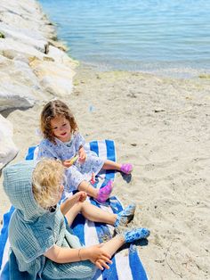 two children sitting on a towel at the beach