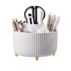 a white cup with pens, scissors and other office supplies in it on a stand