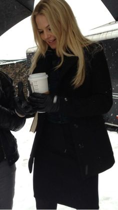 two women standing in the snow holding coffee cups