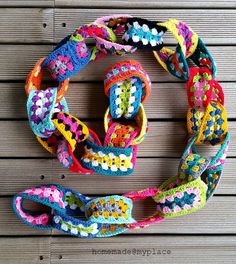 a crocheted multicolored belt is on a wooden surface