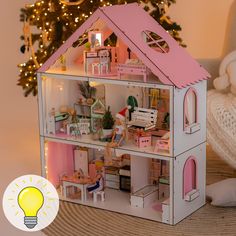 a doll house is shown next to a christmas tree and a lightbulb on the floor