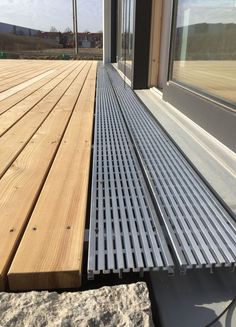 a wooden deck with metal slats next to a window