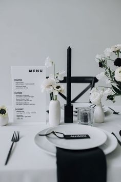 a white table setting with flowers and menu