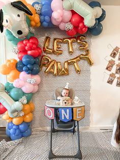 a baby in a high chair next to balloons