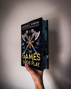 a hand holding up a book about the game's gods play