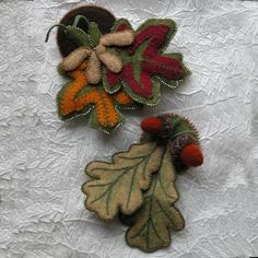 three different colored leaves and acorns sitting on a white tablecloth covered surface