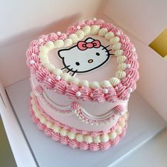 a hello kitty heart shaped cake with pink icing and white frosting on top