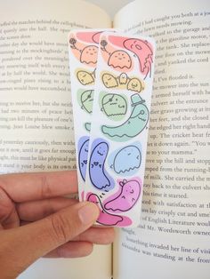 a hand is holding an open book with stickers on it and the pages are colorful