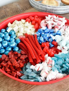 red, white and blue candies in a bowl on a table next to cookies