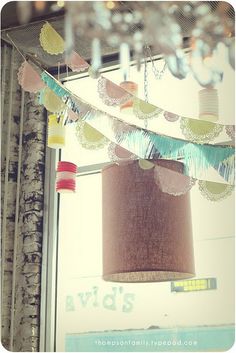 there are many colorful paper decorations hanging from the top of a pole in front of a window