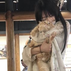 a woman holding a cat in her arms while wearing a kimono and looking at the camera