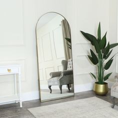 a mirror sitting on top of a floor next to a chair and potted plant