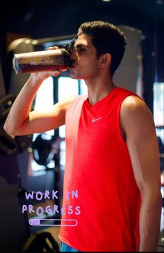 a man drinking from a bottle in a gym