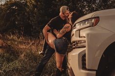 a man and woman kissing in front of a white truck on the side of a road