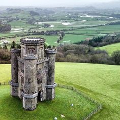 an aerial view of a castle in the middle of a green field with sheep grazing on it