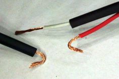 two black and red wires connected to each other on a white surface with one wire wrapped around the ends