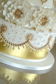 a white and gold wedding cake with flowers on top