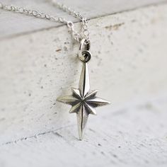 Sterling Silver North Star Necklace. The brightest shining star in the sky, the North Star, or Polaris, has been leading many for centuries. Inspire a graduating friend or loved one to find their true north with this sparkling star in the sky! » Sterling Silver North Star Charm (23.5mm x 11.5mm) with tiny 925 genuine Sterling mark on back. » Sterling Silver Cable Chain (select from drop-down on upper right) » Your jewelry purchase will come beautifully packaged for gift giving. Personalize It: ✧ Spiritual Star Charm Necklaces, Star-shaped Compass Necklace As Gift, Star-shaped Compass Necklace As A Gift, Star-shaped Compass Necklace Gift, Star-shaped Compass Design Necklace As Gift, Star-shaped Compass Design Necklace For Gift, Symbolic Star Necklace Gift, Silver Star-shaped Necklace With Compass Design, Northern Star