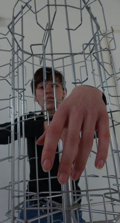 a person holding their hand out in front of a metal structure that looks like he is reaching for something