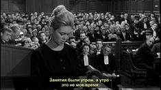 a woman standing in front of an audience with her hand on a book and looking down