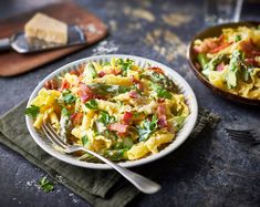 a plate of pasta with asparagus, tomatoes and other toppings on it