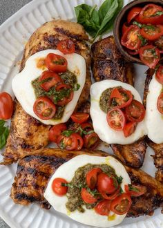 a white plate topped with chicken, tomatoes and mozzarella