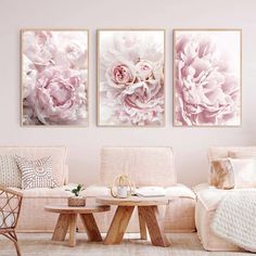 three large pink flowers are hanging on the wall in this living room with white furniture