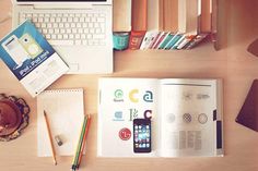 an open book sitting on top of a desk next to a laptop computer and other items