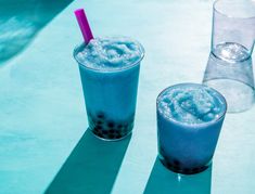 two drinks sitting next to each other on top of a blue table with water in it