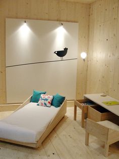 a room with a bed, desk and lamp on the wall next to each other