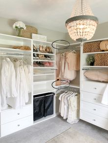 an organized closet with clothes, shoes and other items on shelves under a chandelier