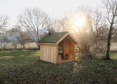 a small wooden outhouse sitting on top of a lush green field