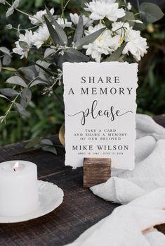 a sign that says share a memory please on it next to a candle and flowers