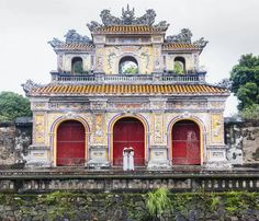 an old building with two red doors and a woman standing in front of the door